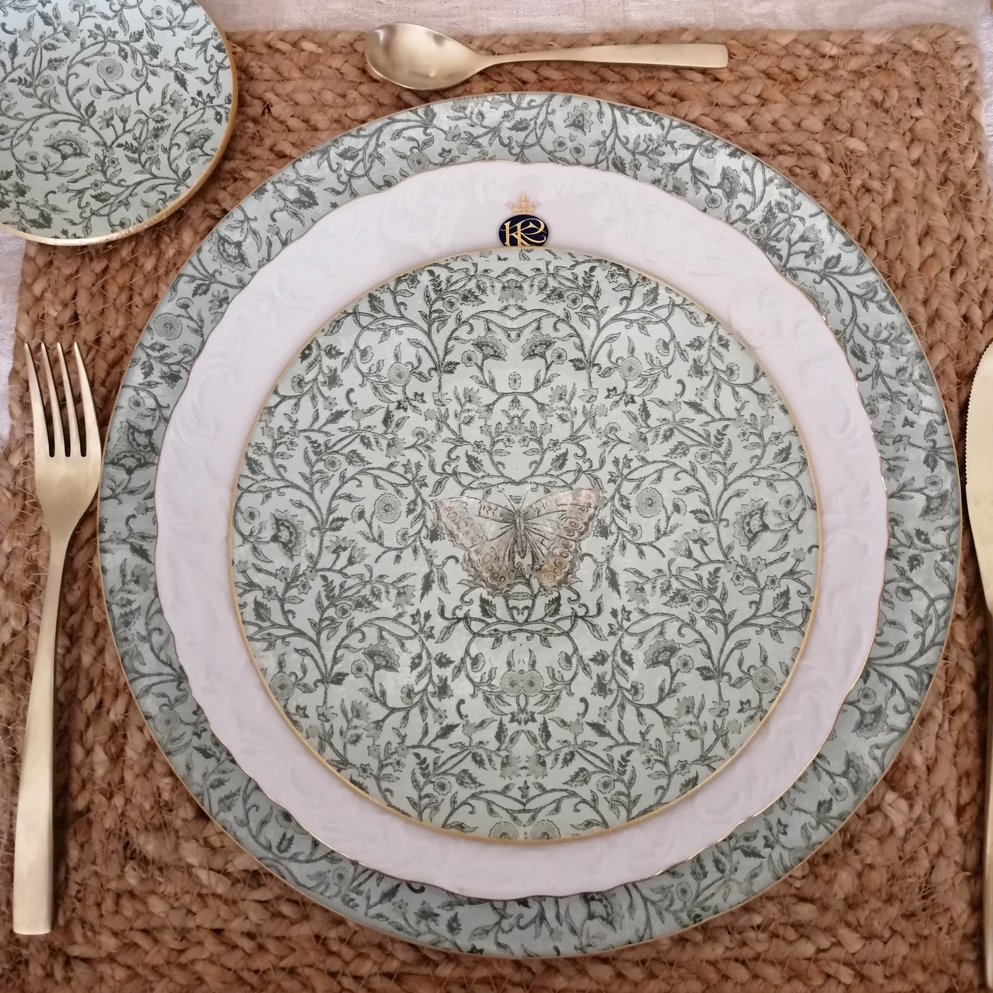 Vajilla artesanal compuesto por plato principal con delicado borde dorado y platito de pan, ambos decorados con un patrón floral en tonos verdes sobre fondo crema. Cada pieza está cuidadosamente elaborada a mano, creando un diseño único inspirado en la tradición de la porcelana clásica europea. Perfecto para: Cenas especiales, regalos únicos, decoración de mesa elegante.
Cada conjunto es una pieza única, pueden existir ligeras variaciones que confirman su carácter artesanal.