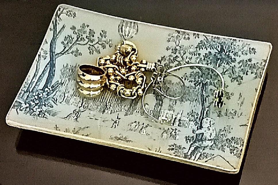 Vaciabolsillo con estampado de escenas románticas de la vida campestre en fondo crema y motivos en azul.