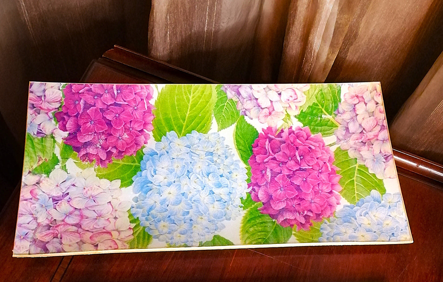 "Bandeja rectangular de 26x13 cm decorada con técnica decoupage, a mano en España. Diseño con patrón de hortensias en acuarela en tonos rosa, azul celeste y lila con hojas verdes sobre fondo blanco"
Esta bandeja es perfecta para: Servir té o café (es ideal para pastas y Plum cake), como bandeja de desayuno (para tostadas o madalenas), para decoración de mesa, como centro de mesa con velas o flores o como bandeja de baño
(Para productos de tocador elegantes)
