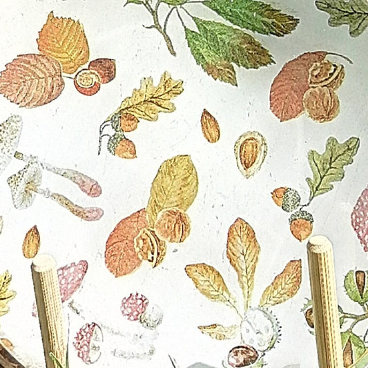 Hojas secas, bellotas, nueces y frutos del bosque se entrelazan en tonos cálidos —ocres, verdes, naranjas y rojizos.