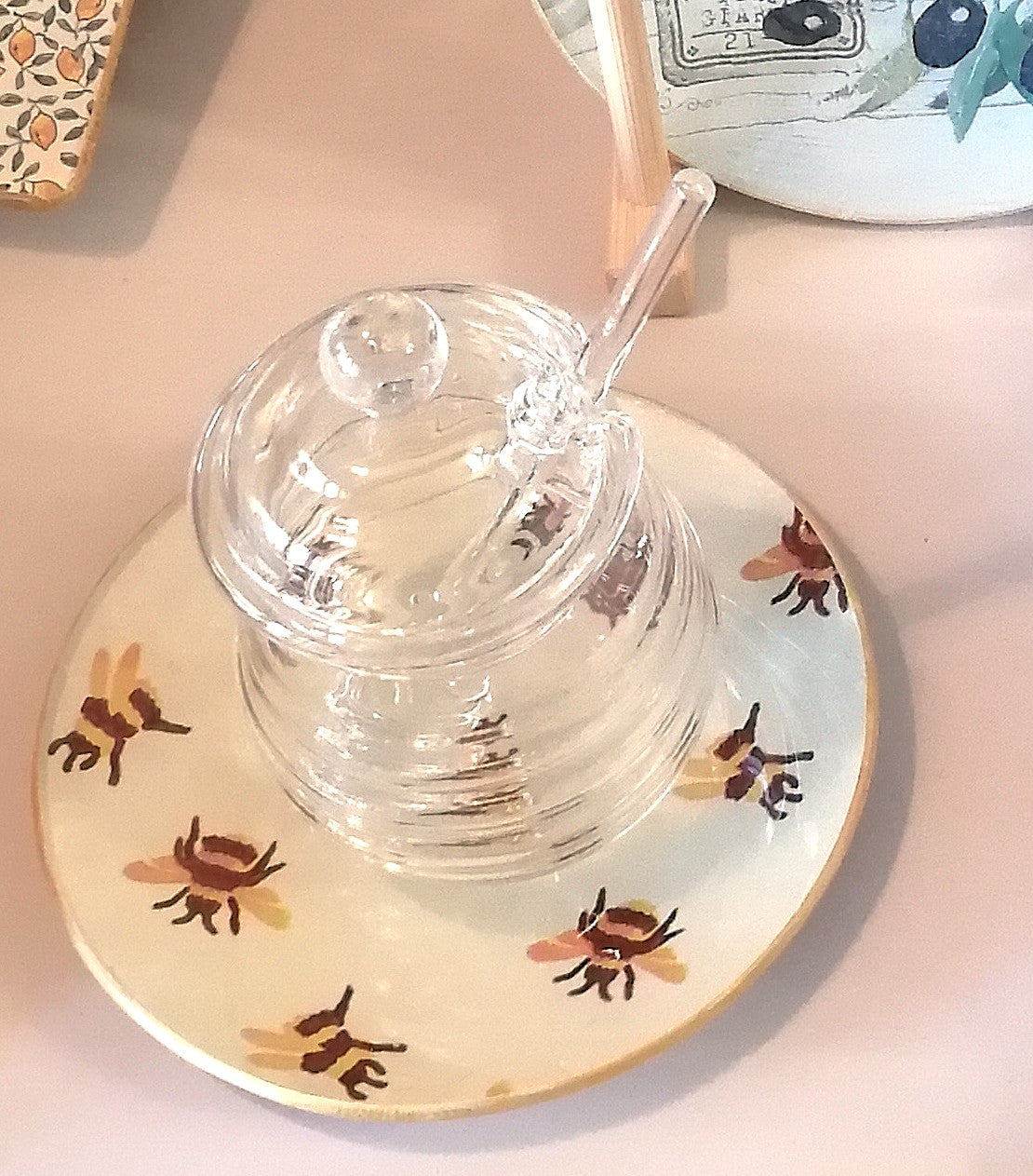 Plato de cristal decorado a mano mediante decoupage. El estampado es de abejitas sobre fondo beige, lo que le da un toque perfecto como platito par la miel.