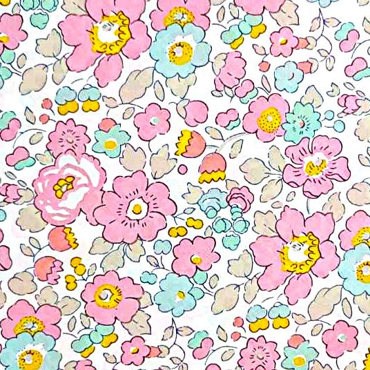 "Estampado de flores liberty pequeñas en rosa, azul celeste y amarillo con centros dorados sobre fondo blanco."