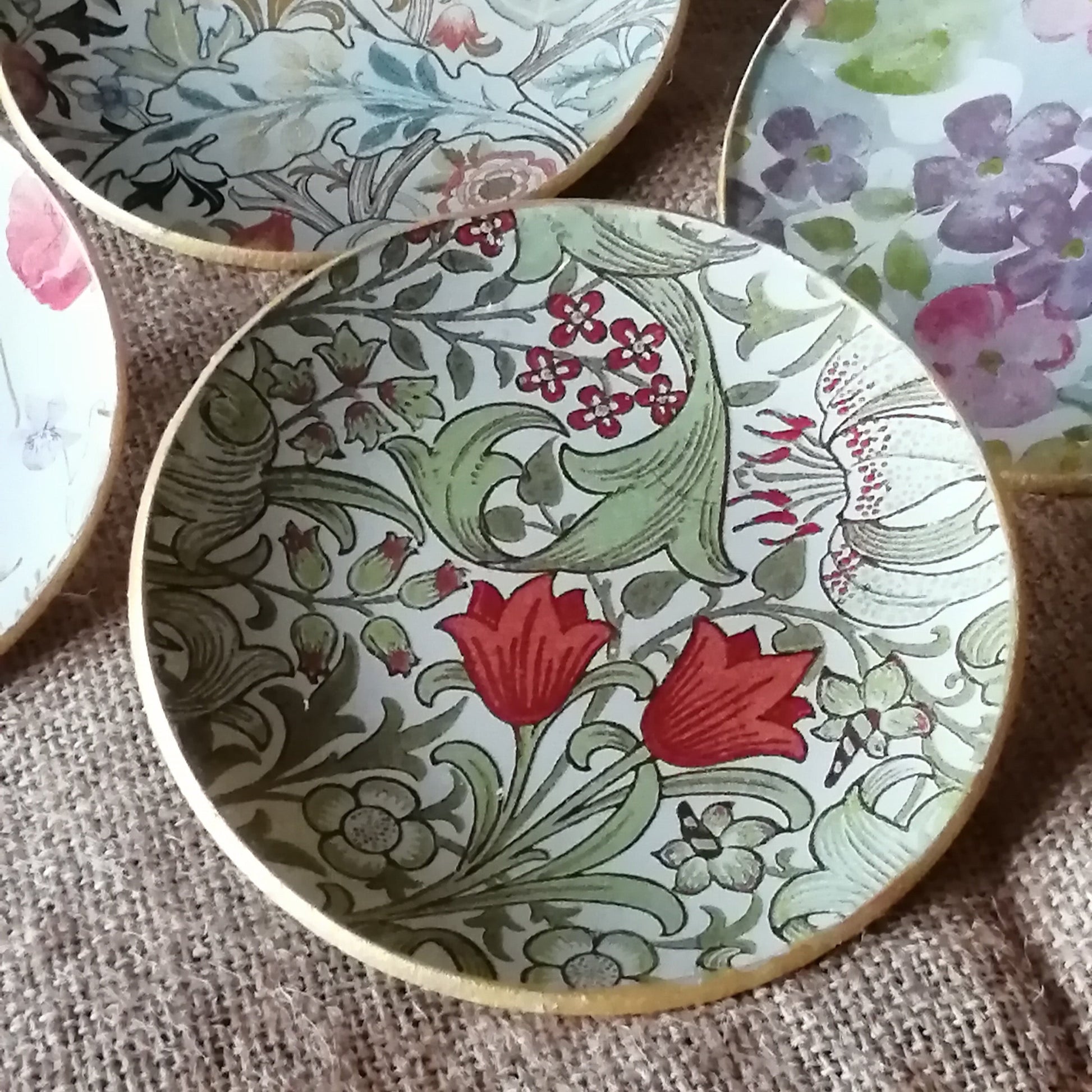 Platito decorado con estampado Golden Lily de William Morris en técnica decoupage. El diseño presenta: Flores corales vibrantes como elemento principal hojas y ramas en tonos verdes suaves pequeñas bayas rojas que añaden detalle fondo en tonos neutros que realza los colores y borde dorado que aporta sofisticación. 
✅ Decoración 100% artesanal
✅ Perfecto para servir pan, bollería o aperitivos.
✅ Tamaño perfecto para uso individual.
✅ Estilo vintage romántico
