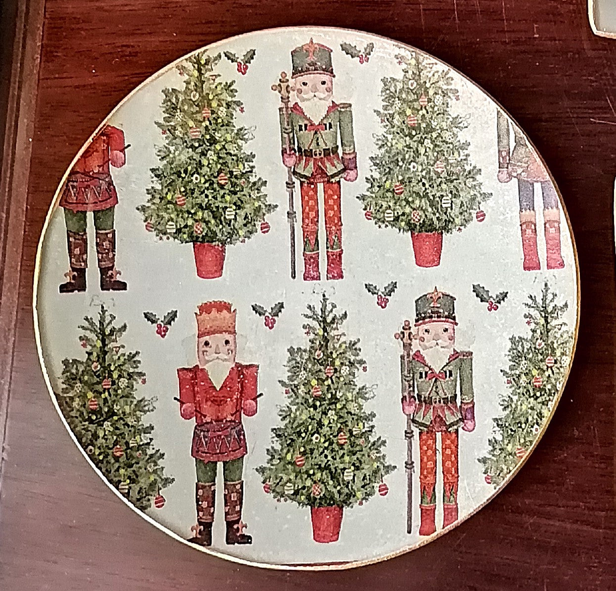 Plato redondo de 15 cm decorado a mano mediante decoupage con estampado de cascanueces y abeto de navidad.
