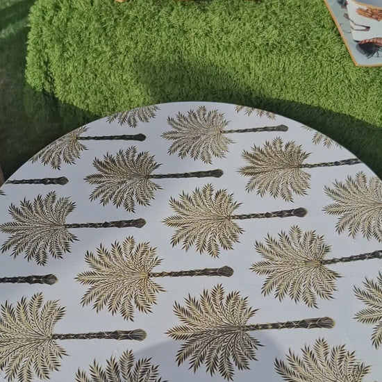 "Tabla giratoria artesanal con estampado de palmeras en tonos dorados y marrones, borde decorado con greca, estilo colonial-tropical"