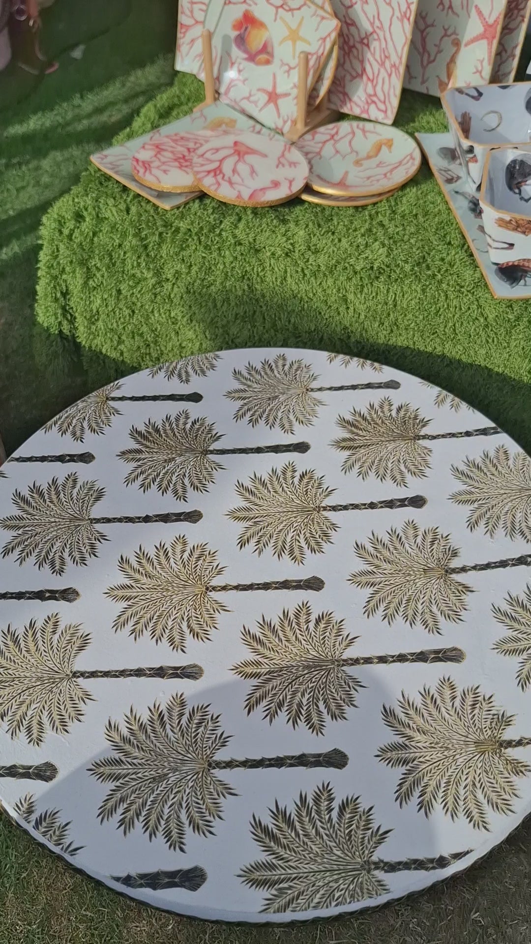 "Tabla giratoria artesanal con estampado de palmeras en tonos dorados y marrones, borde decorado con greca, estilo colonial-tropical"